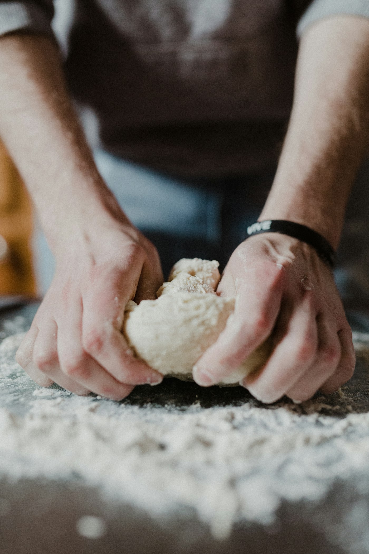 Close-up of hands working dough on a floured surface — real, skilled work